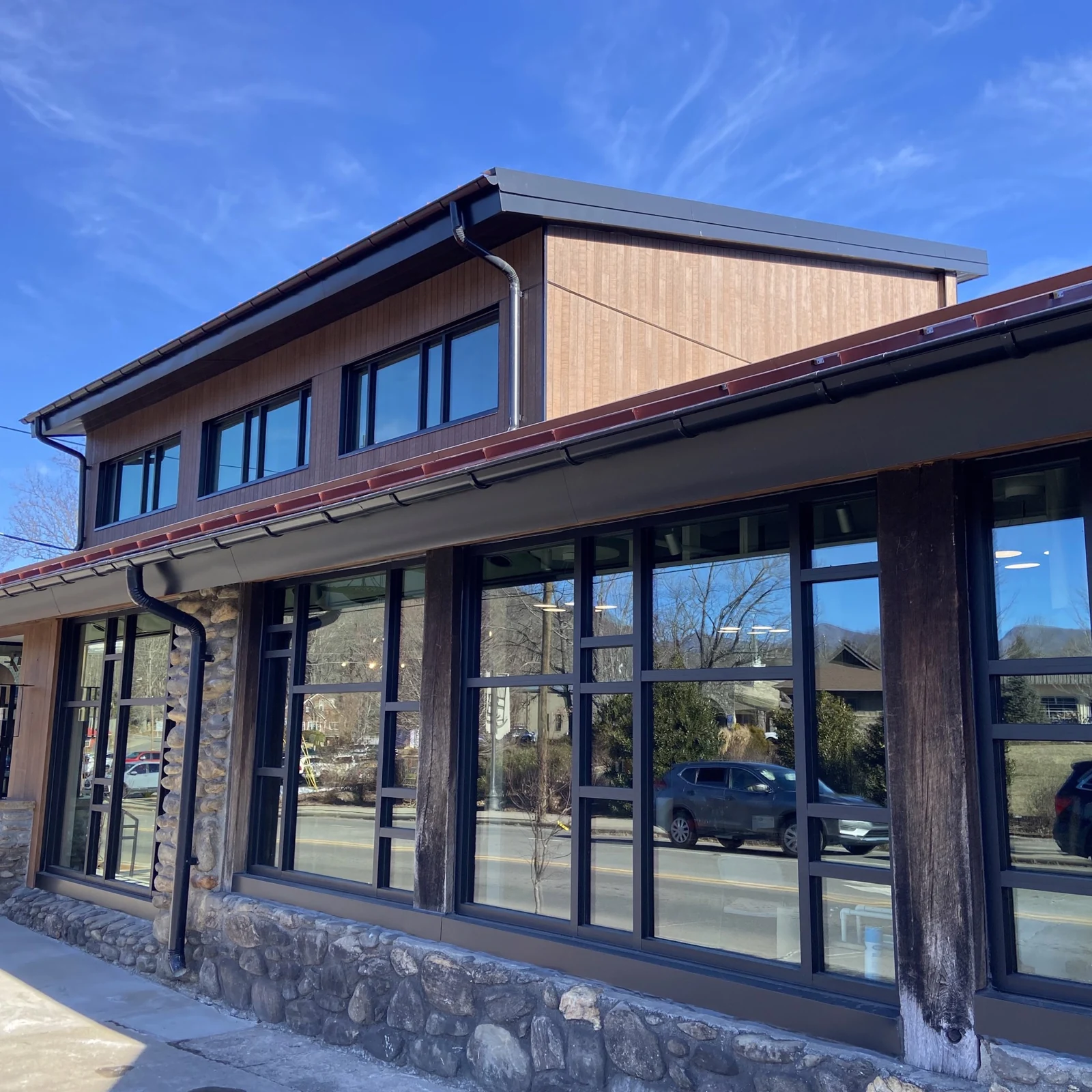 Completed North Carolina Glass Center exterior in Black Mountain, with a stone base, tall windows and upper-story siding