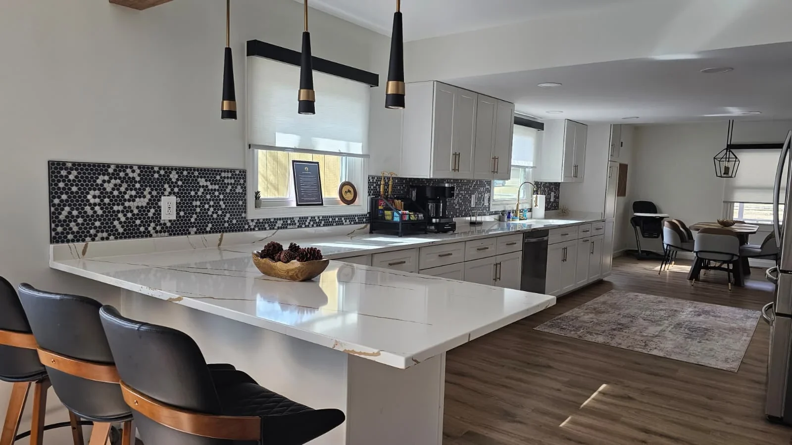Mojo Manor kitchen with quartz counters, white cabinetry and black-and-brass pendant lights