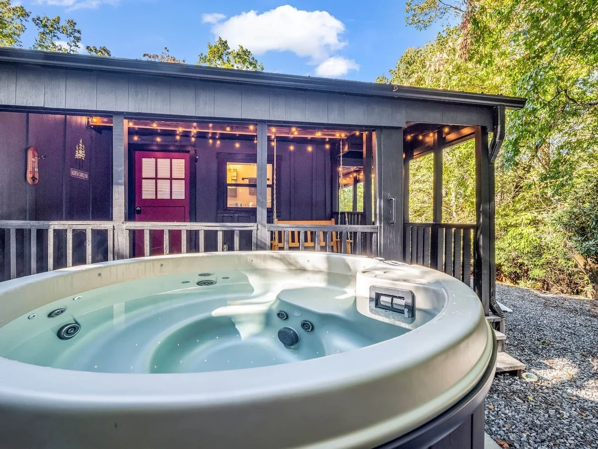 Open hot tub at Stonehaus beside the finished covered porch and red doors