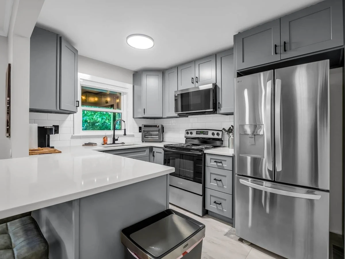 Finished Stonehaus kitchen with gray cabinetry, light countertops and stainless steel appliances